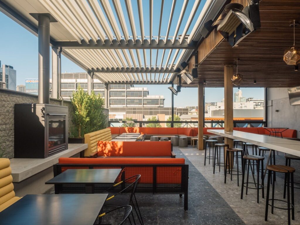 empty rooftop bar and restaurant with bright orange loungers and gas heaters