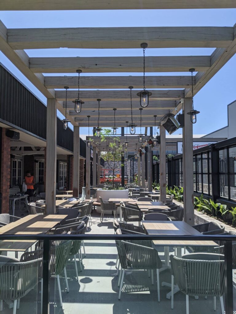 Outdoor seating at empty restaurant on a bright blue sky day and gas heaters